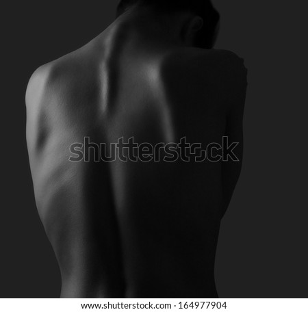 Beautiful woman back on dark background. Black and white portrait