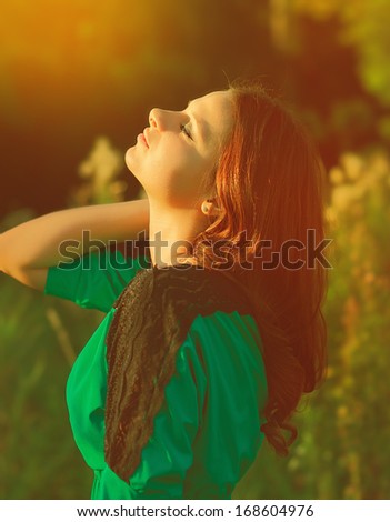 Beautiful woman enjoy sunshine in summer day on yellow background. Girl looking up with closed eyes