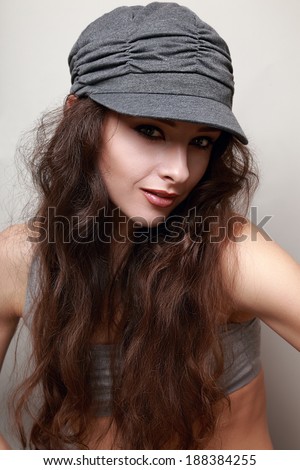 Beautiful smiling long hair trendy woman in cap. Hip-hop style