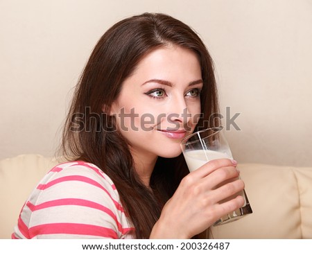 Happy woman drinking milk from glass sitting on sofa