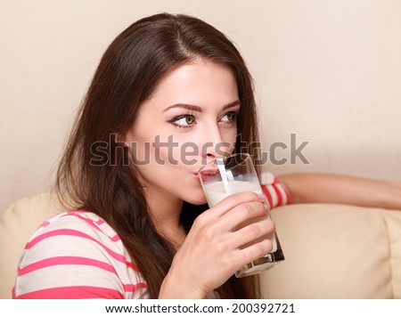 Beautiful woman drinking milk sitting on sofa