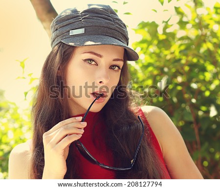 Sexy fashion female model posing in cap with sun glasses outdoors summer background
