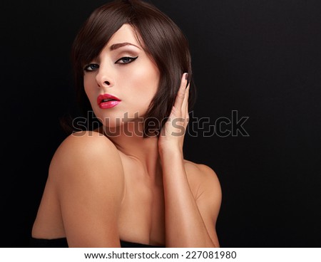 Beautiful bright makeup woman holding hand the short healthy hair and looking sexy on black background with empty copy space