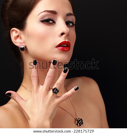 Beautiful fashion model with jewelry accessories and black fingernail looking sexy. Red lips makeup. Closeup