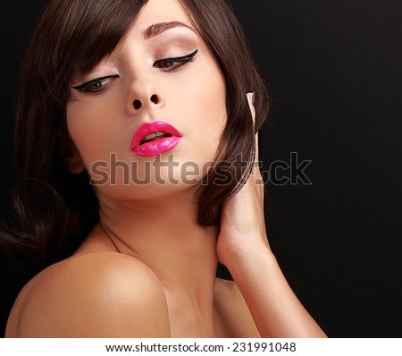 Beautiful sexy makeup woman with pink lipstick and black eyeliner on black background