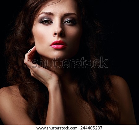 Beautiful mystery woman face kissing her hot pink lips on black background. Closeup
