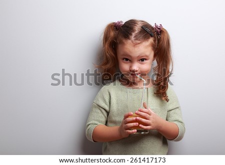 Funny emotion kid girl drinking juice from grass and looking