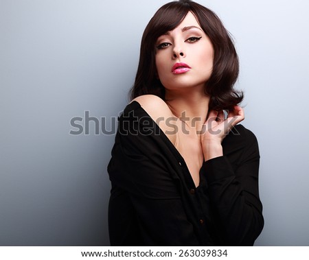 Sexy hot makeup woman with short hairstyle posing in black shirt on blue background with empty copy space