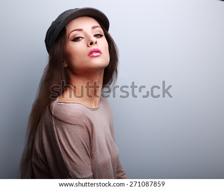 Sexy makeup woman in cap posing in modern blouse on blue background