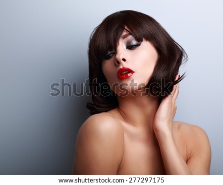 Sexy female model posing with black short hairstyle on blue background with empty copy space.Closeup