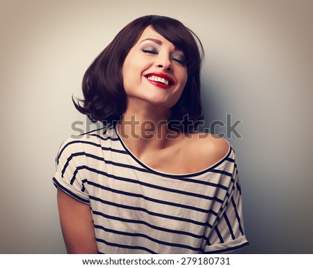 Smiling young woman with closed eyes laughing with short hair style. Closeup vintage portrait with empty copy space