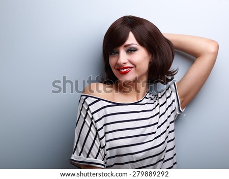 Smiling happy young woman in casual dress relaxing on blue wall background