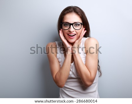 Excited surprising fun young woman with open mouth in glasses on blue background with empty copy space