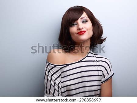 Funny young woman grimacing with short black hair style on black background