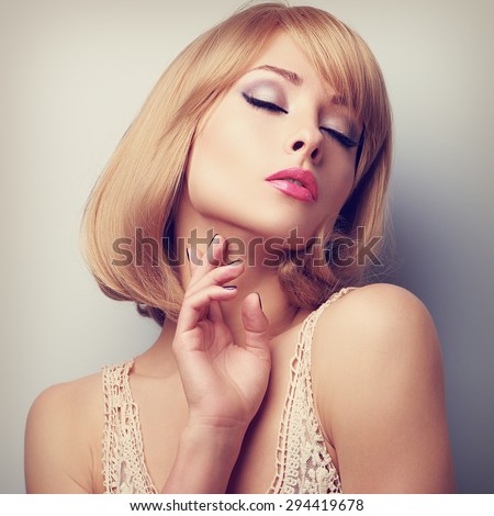 Beautiful blond short hair woman with closed eyes touching neck skin. Toned closeup portrait. Bright perfect makeup