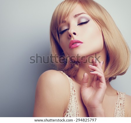 Beautiful blond hair woman with closed makeup eyes touching neck perfect skin. Toned closeup portrait