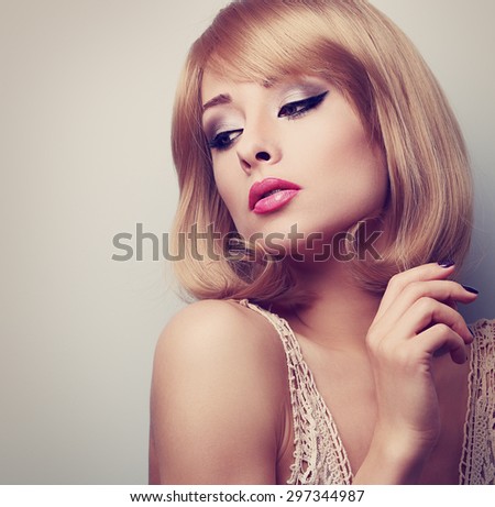 Beautiful blond makeup woman with short hair style looking down. Toned color closeup portrait with empty copy space