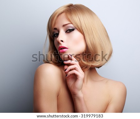 Elegant makeup blond woman with manicured nails posing on blue background