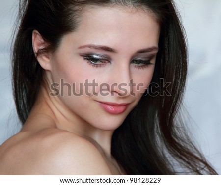 Closeup portrait of beautiful young woman with long hair, perfect face and naked shoulders looking down