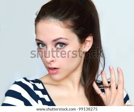 Closeup portrait of a surprised young woman holding hand the hair and looking with big eyes and opened mouth isolated