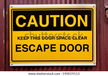 Yellow and black escape door sign on a building exterior