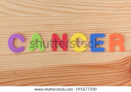 Foam letters spelling out the word cancer on a wooden background