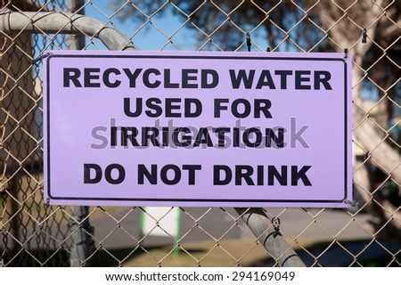 A purple recycled water warning sign attached to a fence