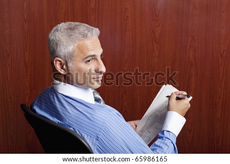 newspaper stock quotes. stock photo : Businessman sitting in his office looking at stock quotes in
