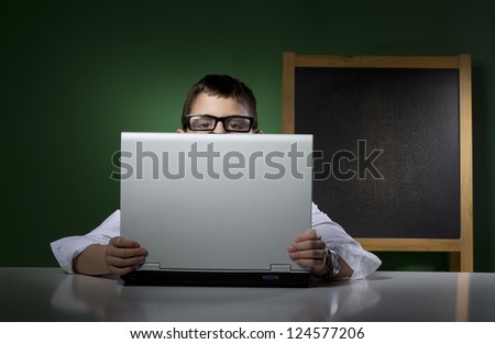 Schoolboy peeps behind computer notebook