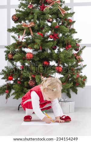 Baby girl writing letter to Santa and christmas tree