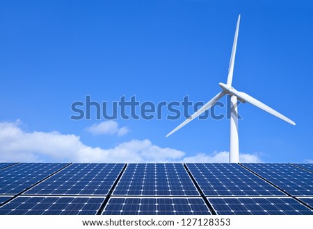 Solar panels and wind turbine against blue sky