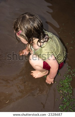 a little girl playing in the mud