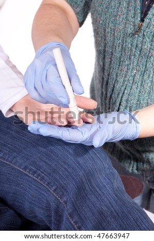 gloved hands pricking a finger to draw blood