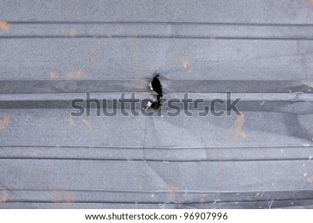 A hole torn in ridged metal siding