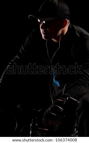 Man on mountain bike in darkness wearing sunglasses and mp3 player
