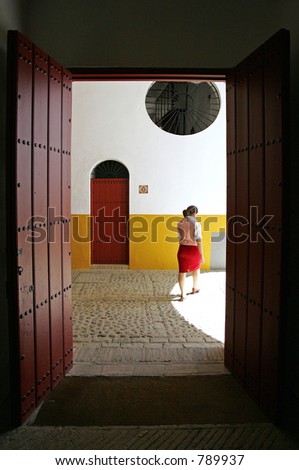 Young female Spanish tour guide walking through door in large bullring in Seville Spain