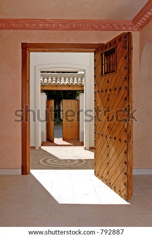 Looking through the open front door of a villa in Spain into the garden with another open door on a sunny day