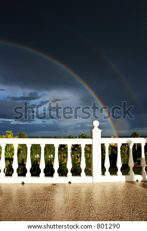Terrace or Spanish villa with views to moody stormy cloudy sky and rainbow in the evening