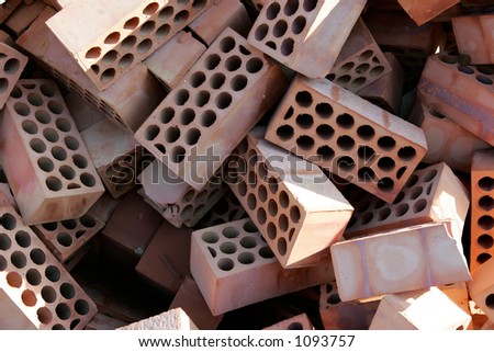Jumbled, messy pile of red bricks with circles or holes in them
