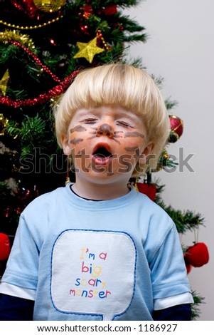 Young boy trying to be scary and pulling a funny face with tiger paint