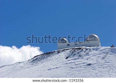 Snowy ski slopes of Pradollano ski resort in the Sierra Nevada mountains in Spain with large telescope and observatory