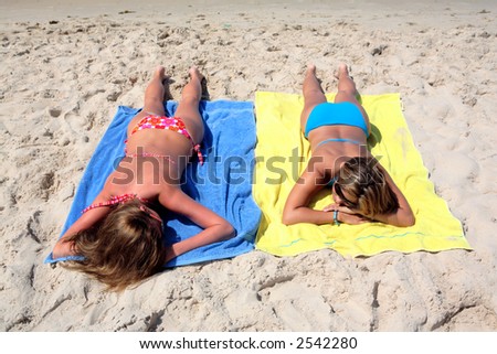 stock photo Two sexy young girls in bikinis laying on a sunny beach on 