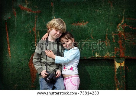 Two young children stand still while they have their photo taken against a grunge background