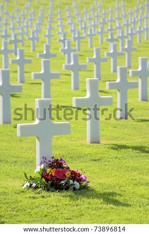 Flowers laid by cross shaped headstone of military grave