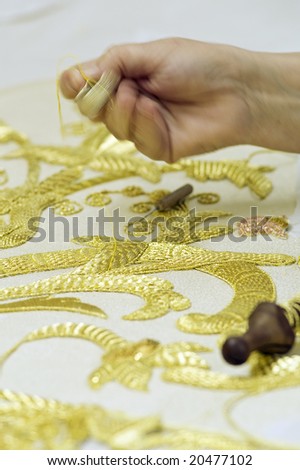 The first plane of a woman realizing embroidery in gold