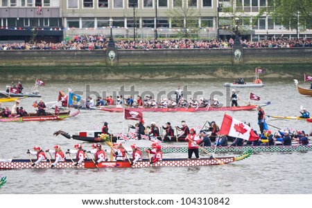 LONDON, UK-JUNE 3: Dragon boats are rowed down the river Thames, watched by huge crowds in the flotilla of a 1,000 boats  for the Queen\'s Diamond Jubilee Pageant. June 3, 2012 in London UK.