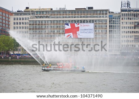 LONDON, UK-JUNE 3: The Fire Flash a London Fire Brigade, Fire Boat sprays water in the flotilla of a 1,000 vessels. Part of the Queen\'s Diamond Jubilee Pageant. June 3, 2012 in London UK.