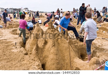 MARGATE, UK-JUNE 29: The Family Planners team build a giant sand castle in the RIBA sandcastle Challenge, on Margate\'s main sands, watched by many visitors to the beach. June 29, 2013 Margate UK