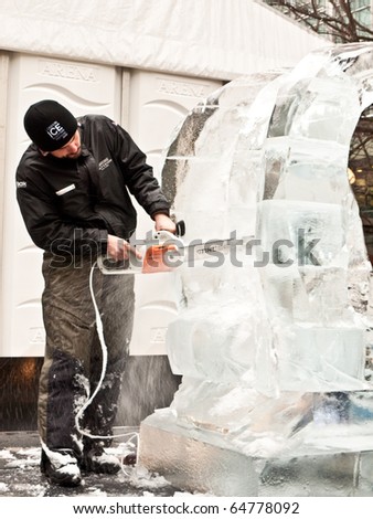 LONDON, UK - JANUARY 15: Ice Sculptor at Work With Power Tool at the Annual London Ice Sculpture Festival Competition.Canary Wharf, London January 15 2010