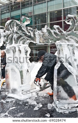 LONDON, UK- JANUARY 15: A unidentified member of the African Ice Sculpting Team at Work with a Chainsaw, at the Annual London Ice Sculpting Festival. January 15, 2011 in London, UK.